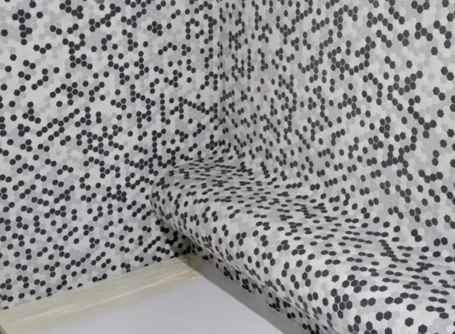 Banco curvo revestido con mosaico geométrico dentro de una ducha